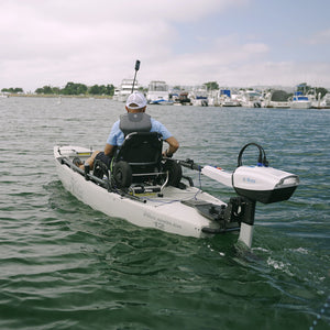 Person in a kayak with motor on a body of water, surrounded by other boats.