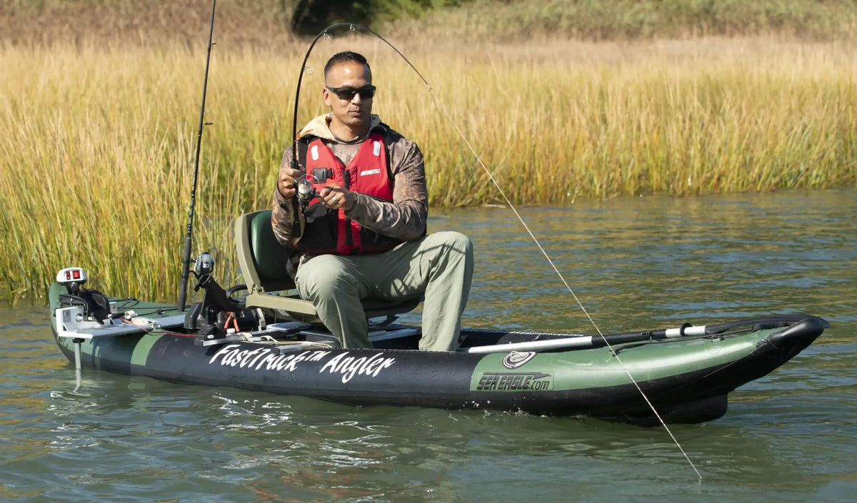 Man fishing from a green and black Sea Eagle FastTrack Angler inflatable kayak with two fishing rods.