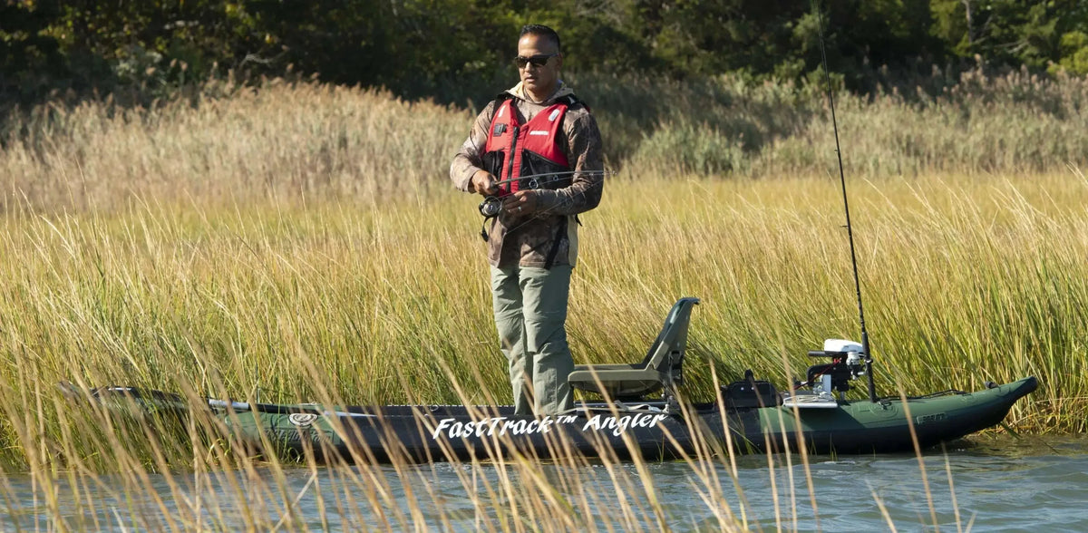 Man fishing from a green Sea Eagle 385fta FastTrack Angler inflatable kayak in tall grass.
