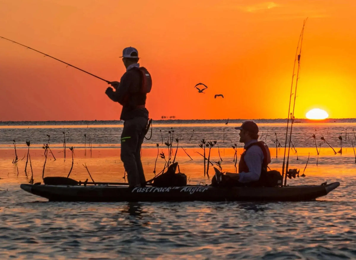Two anglers in a green Sea Eagle 385fta FastTrack Angler inflatable kayak at sunset.