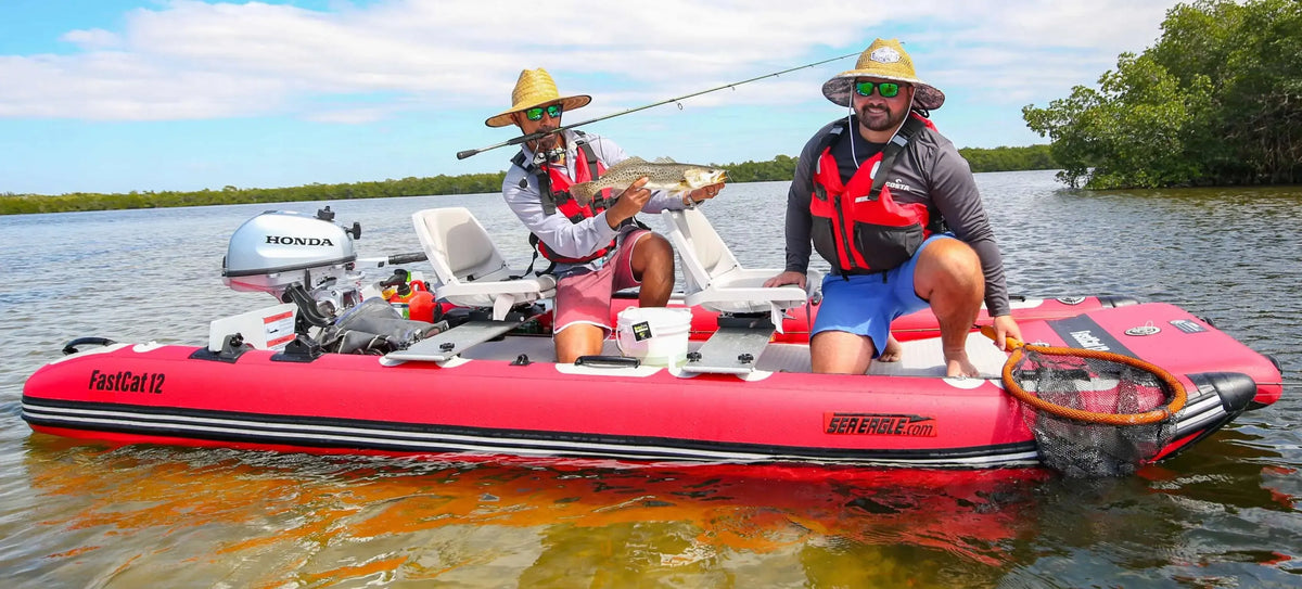 Two men fishing from a red Sea Eagle FastCat12 inflatable catamaran with a Honda outboard motor.