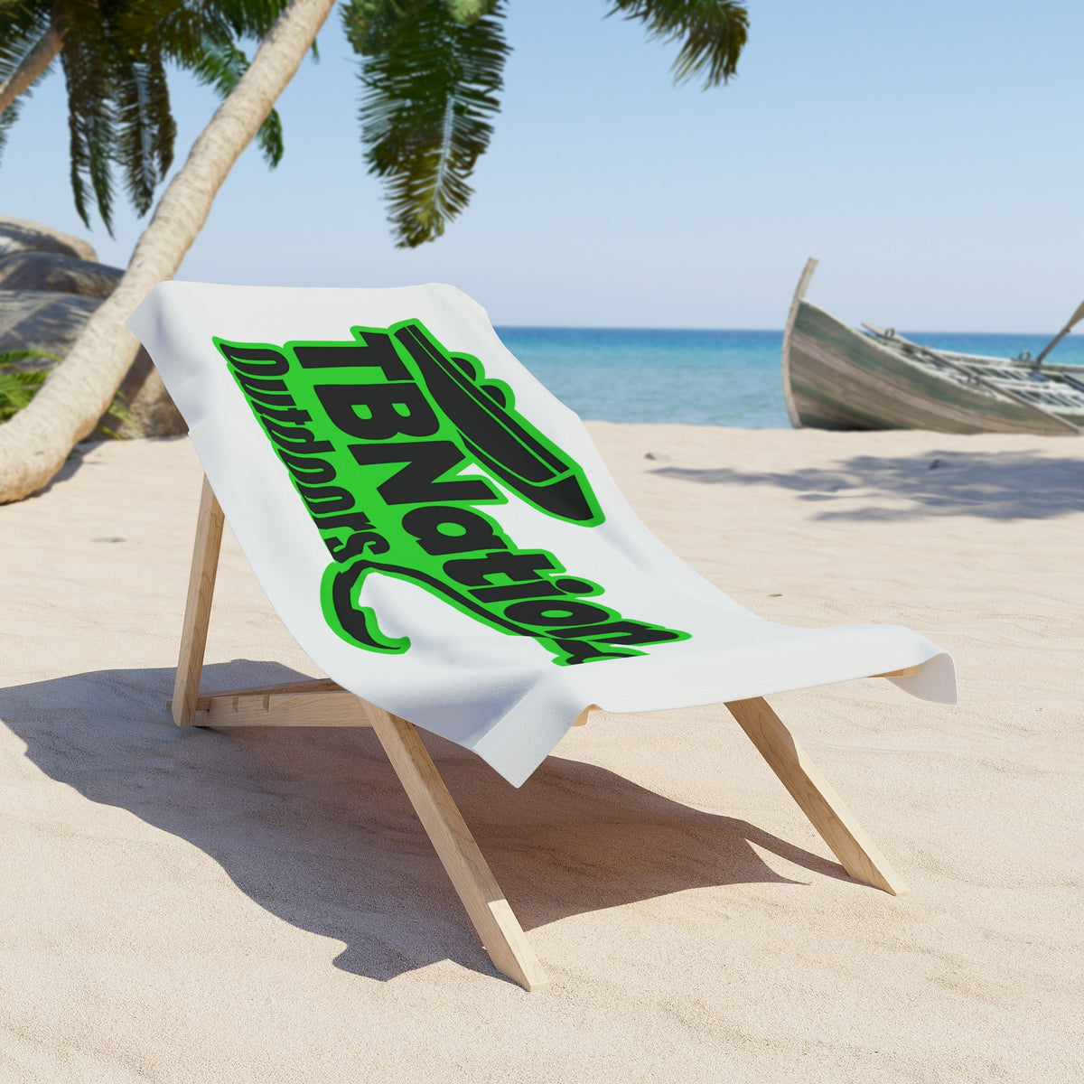 Beach chair with a towel featuring 'TBNation' branding on a sandy beach with palm trees and ocean in the background.