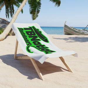 Beach chair with a towel featuring 'TBNation' branding on a sandy beach with palm trees and ocean in the background.