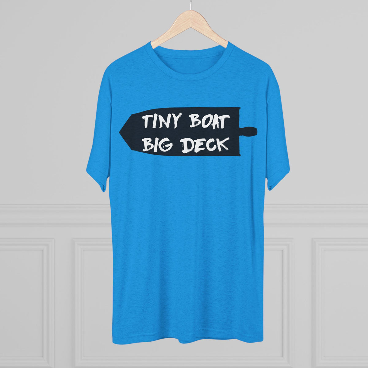 Blue t-shirt with 'Tiny Boat Big Deck' text on a hanger against a gray background