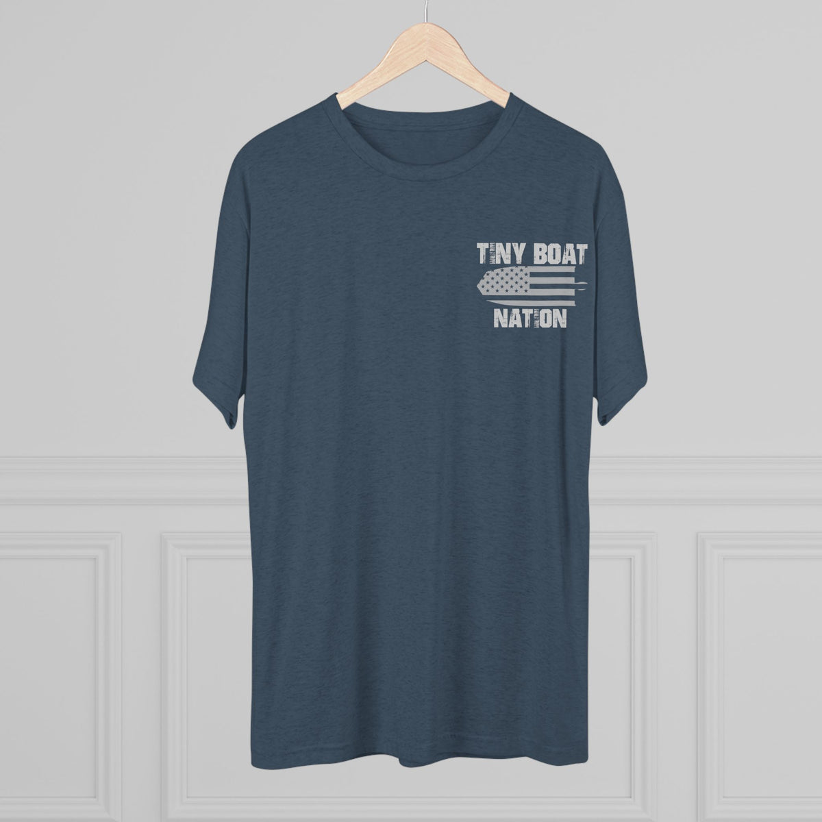 Navy blue t-shirt with 'Tiny Boat Nation' text on a hanger against a gray background