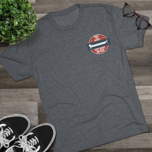 Gray t-shirt with a graphic design on a wooden surface with sneakers and a plant.