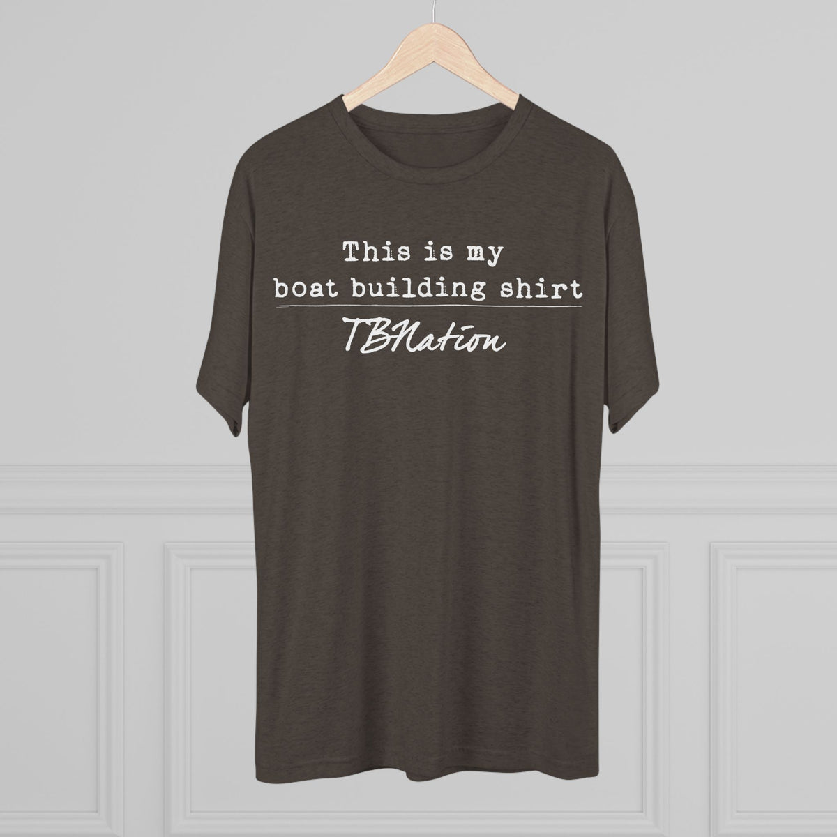 Brown t-shirt with text on a hanger against a gray background