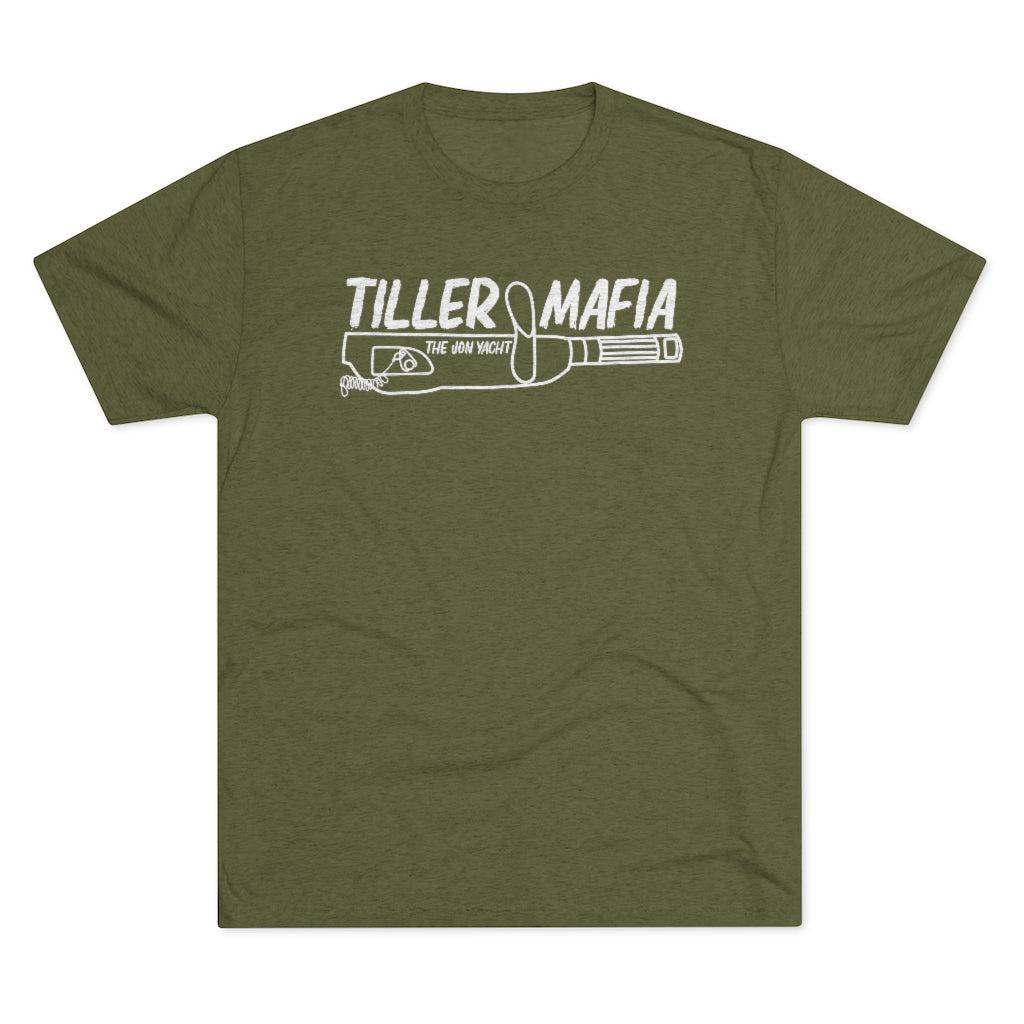 An olive green short-sleeve t-shirt with a white graphic print on the chest reading 'TILLER MAFIA' and 'THE JON YACHT' above a revolver illustration, shown on a plain white background.