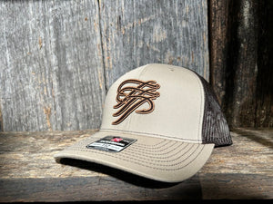 Beige trucker cap with brown logo on a wooden surface
