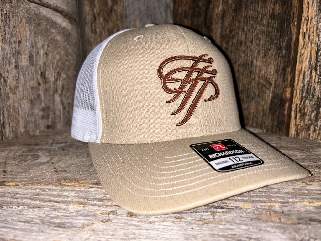 Beige and white cap with brown logo on a wooden surface
