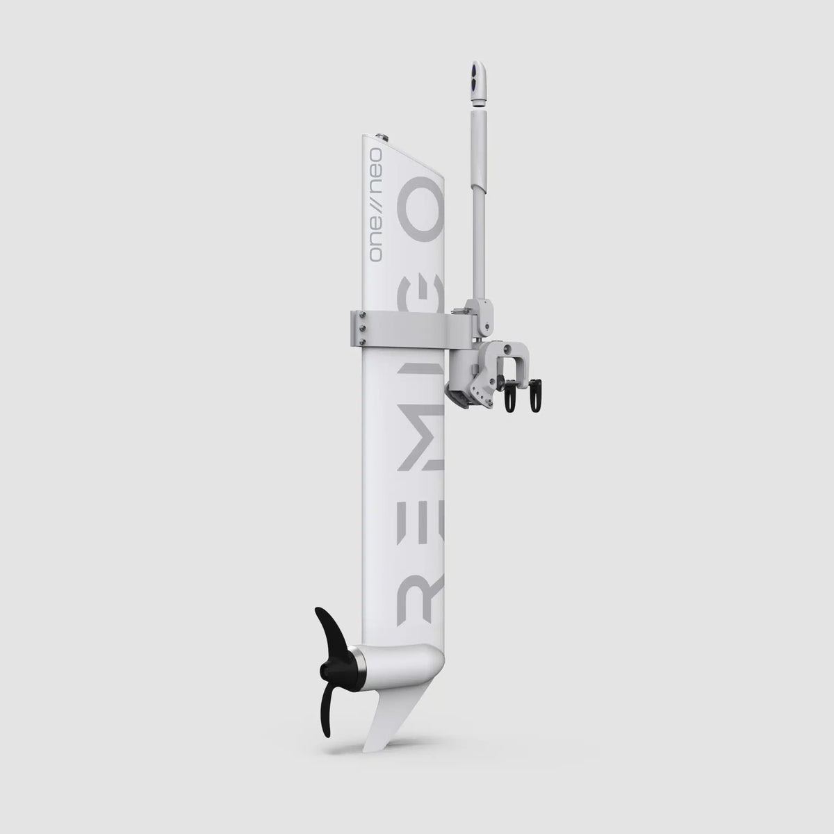 A studio product shot of the Remigo One Neo electric outboard motor against a plain grey background. The motor features a unique, flat, rudder-like white body with "REMIGO" branding, a black two-blade propeller at the bottom, and an adjustable transom mounting bracket.