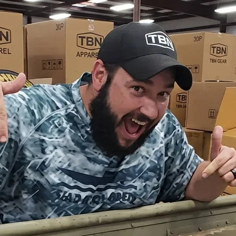 Chris Simmons, head of TBNation Southeast, smiling and giving two thumbs up in the warehouse surrounded by TBN Gear boxes, representing the company's friendly customer service and team spirit