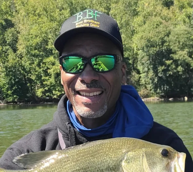 Naeem Green, TBNation team member, smiling while holding a freshly caught fish on the water, representing a passion for fishing, boating, and the outdoor lifestyle.