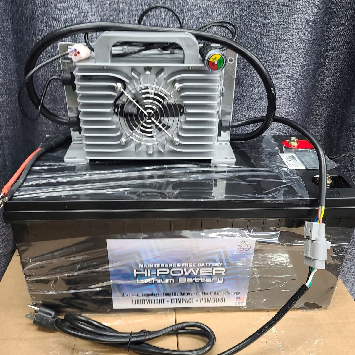 Black Hi-Power 48V lithium battery with a gray charger, cables, and power cord.