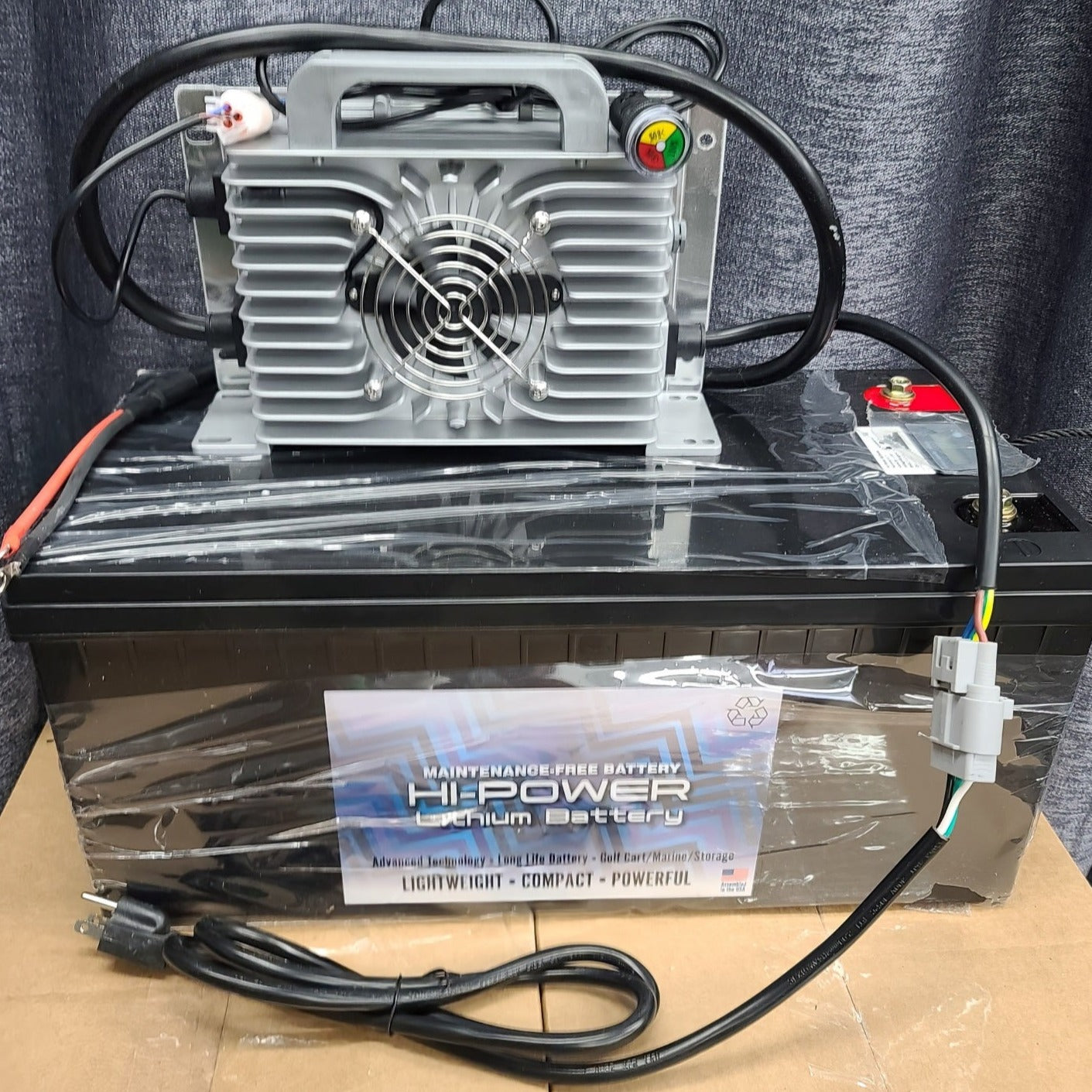 Black Hi-Power 48V lithium battery with a gray charger, cables, and power cord.