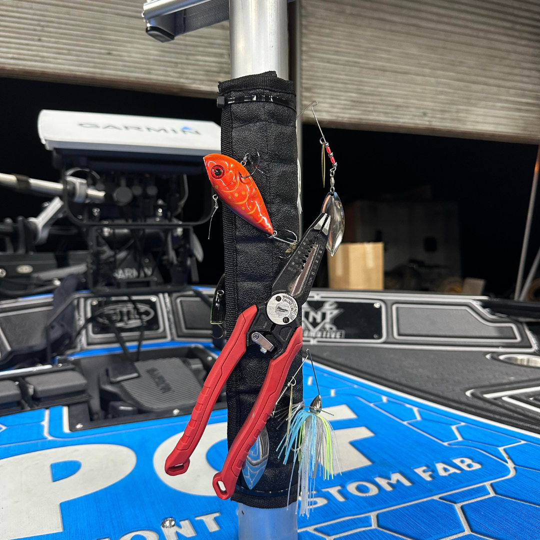 Black Magnalure Wrap with velcro closure holding fishing lures and red pliers on a boat pedestal.