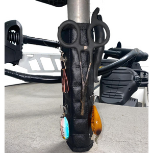 Black Magnalure magnetic wrap with velcro closure on a boat pedestal, holding fishing lures, scissors, and pliers.