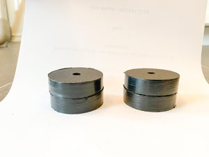 Two black round UHMW motor clamp spacers, 1-inch thick, with a center hole, stacked on white paper.