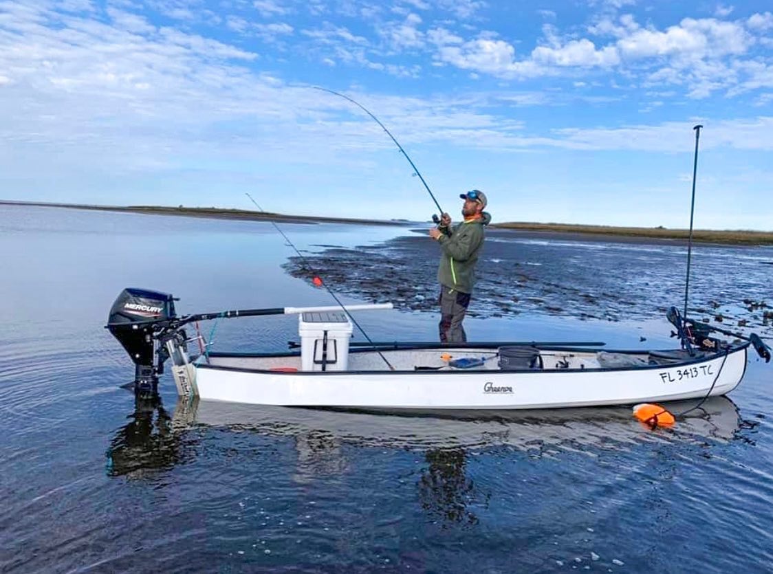 White OnTheFly Electric Jackplate on a small boat with a Mercury outboard, used by a man fishing.