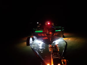 Boat launching at night with bright white and green Plashlight LED strips illuminating the water.