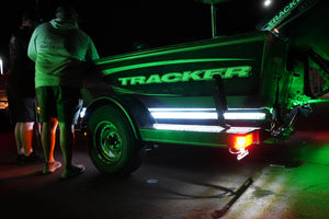Green LED light strips illuminate a Tracker boat on a trailer at night.