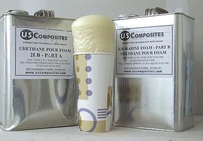 Two silver US Composites cans of 2 Lb density urethane pour foam, with a paper cup of expanded foam in the center.