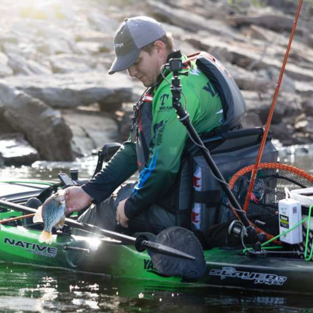 Man in kayak with green Railblaza Camera Boom 600 mounted, holding a fish.