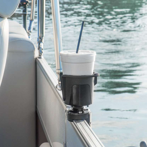 Black Railblaza DrinkHold mounted on a boat railing, holding a white foam cup with a straw.
